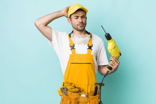 young adult hispanic man smiling happily and daydreaming or doubting. worker and drill concept - 写真・画像