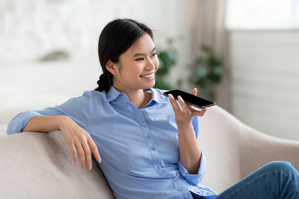 Closeup of cheerful asian woman holding smartphone, recording voice message - Foto, Imagen