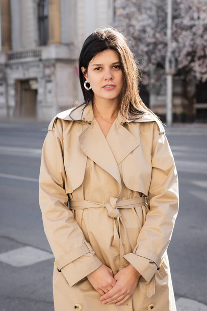 brunette woman in elegant beige coat standing on street in vienna  - Фото, зображення