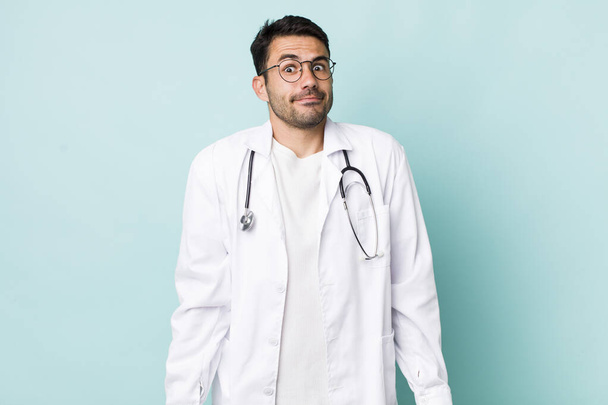 young adult hispanic man shrugging, feeling confused and uncertain. physician concept - Фото, изображение
