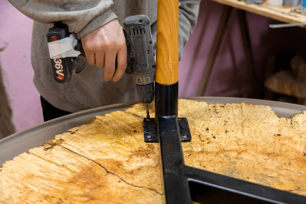Closeup of carpenter screwing the table leg with a screwdriver - Foto, imagen