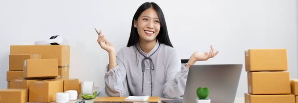Young Asian woman is an online merchandiser and is currently managing conversations and receiving orders from customers via the Internet, Selling products online or doing freelance work at home concept. - Photo, Image