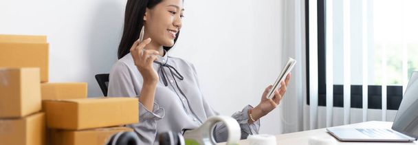 Молоді азіатські жінки продають товари онлайн і користуються мобільними телефонами для того, щоб спілкуватися з клієнтами, щоб підтвердити замовлення, продавати товари онлайн або робити вільну роботу вдома концепція. - Фото, зображення
