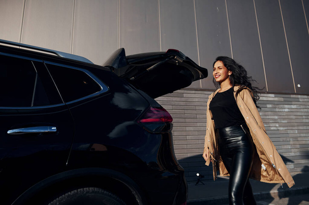 Young woman in black leggins walks out from her modern car. - Φωτογραφία, εικόνα