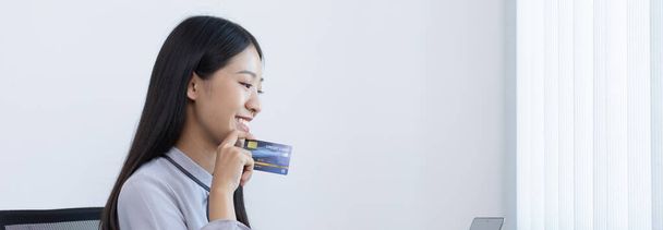 Young women are happy to shop online and hold credit cards to make payments over the Internet in the laptop, Online shopping and Credit card payment. - Фото, изображение