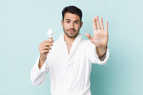 young adult hispanic man looking serious showing open palm making stop gesture. shaving concept - Foto, Imagen
