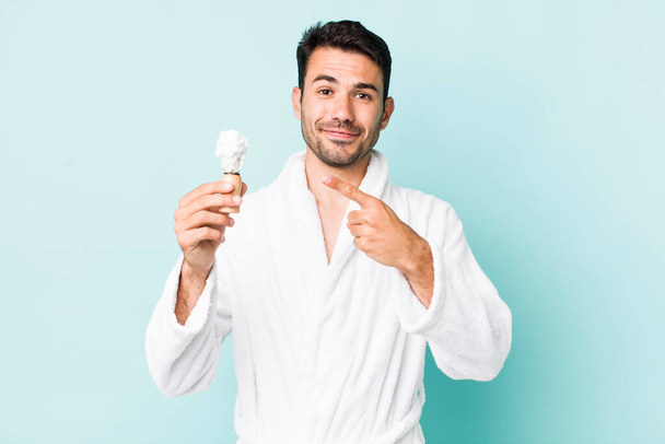 young adult hispanic man smiling cheerfully, feeling happy and pointing to the side. shaving concept - Φωτογραφία, εικόνα