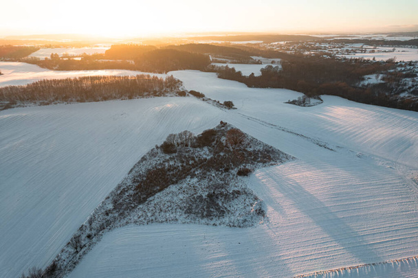 Veduta aerea drone di campi innevati invernali e foresta al tramonto - Foto, immagini