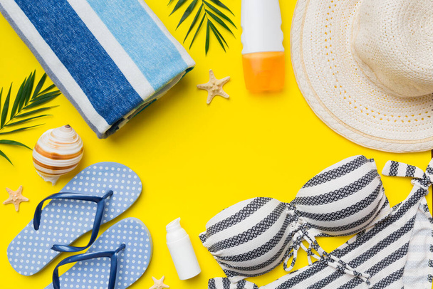 Woman swimwear and beach accessories flat lay top view on colored background Summer travel concept. bikini swimsuit, straw hat and seasheels. Copy space Top view. - 写真・画像