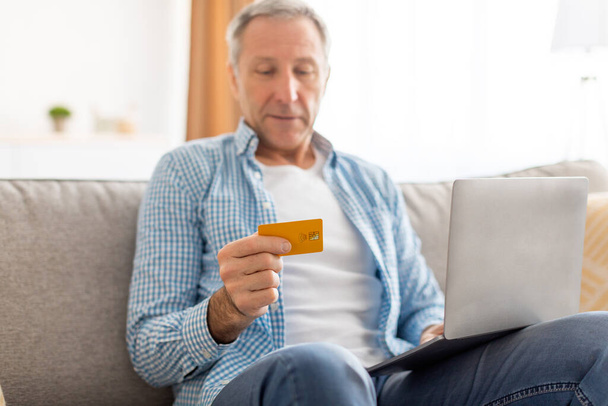 Mosolygós érett férfi használ PC és hitelkártya otthon - Fotó, kép
