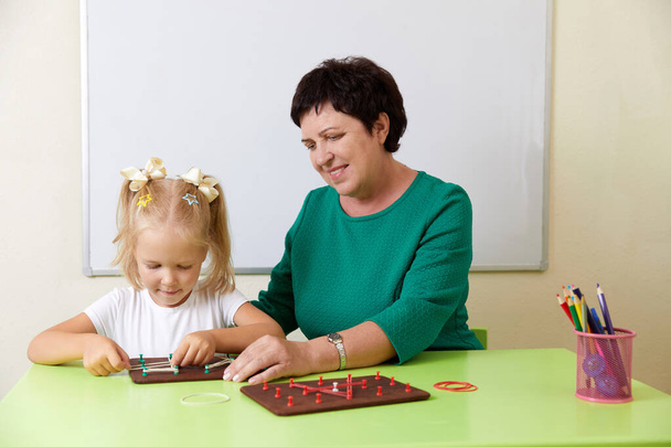 Erwachsene Frau bringt Kind das Alphabet bei. Entwicklung eines Feinmotorikkonzepts - Foto, Bild