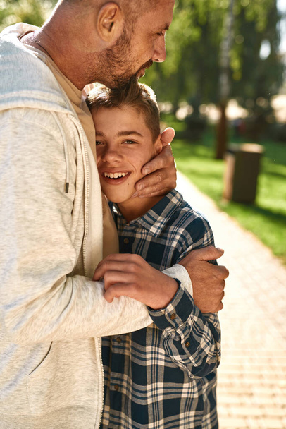 Father hug joyful teenage son with cerebral palsy - Foto, imagen