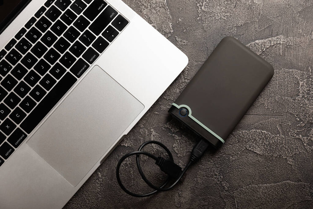 External HDD and laptop on black cement background. Place to copy - 写真・画像