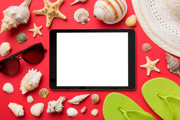 Επίπεδη σύνθεση lay με tablet και αξεσουάρ παραλίας σε χρωματιστό φόντο. Tablet υπολογιστή με κενό οθόνη mock up με αντίγραφο χώρου. - Φωτογραφία, εικόνα