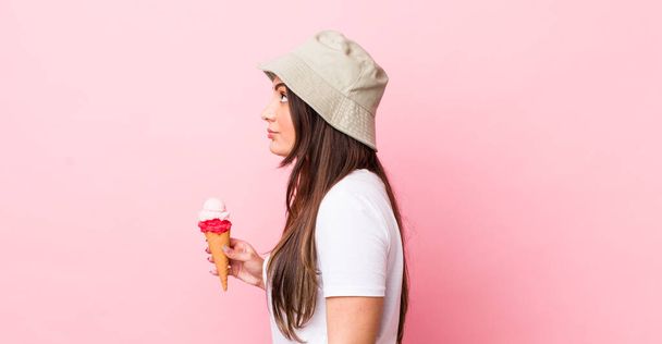 young pretty woman on profile view thinking, imagining or daydreaming. summer and ice cream concept - 写真・画像