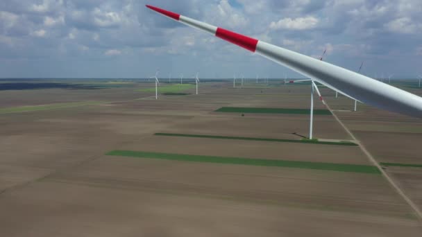 Por encima de la vista, movimiento dolly, sobre la granja de grandes turbinas de energía eólica están de pie entre los campos agrícolas, la generación de energía eléctrica renovable limpia para el desarrollo sostenible. - Imágenes, Vídeo
