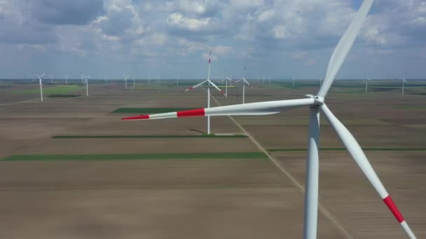 Por encima de la vista, movimiento dolly, sobre la granja de grandes turbinas de energía eólica están de pie entre los campos agrícolas, la generación de energía eléctrica renovable limpia para el desarrollo sostenible. - Metraje, vídeo