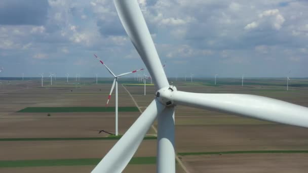 Above view on farm of large wind power turbines are standing among agricultural fields, generating clean renewable electrical energy for sustainable development. - Filmagem, Vídeo