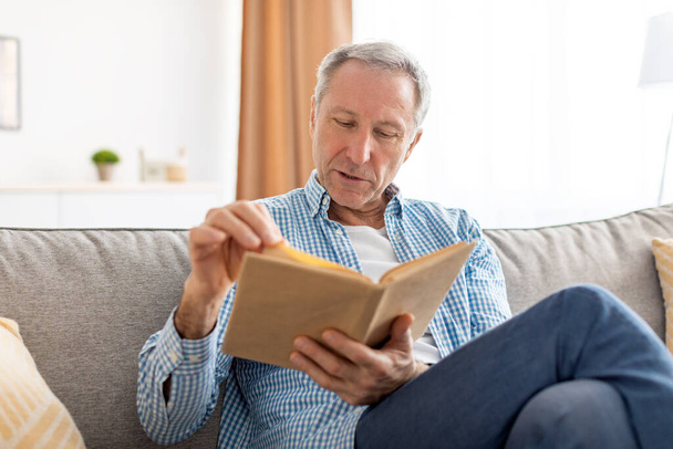 Portret dojrzałego mężczyzny czytającego książkę w domu - Zdjęcie, obraz