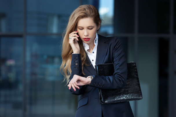 Geschäftsfrau telefoniert und schaut auf ihre Uhr - Foto, Bild