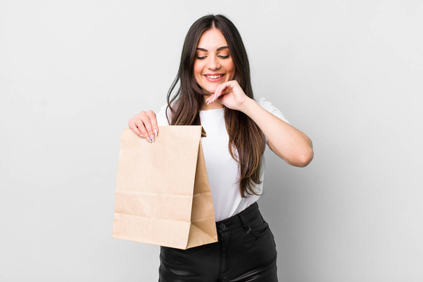 young pretty woman smiling with a happy, confident expression with hand on chin. take away food concept - Фото, изображение