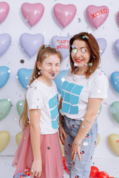 beautiful young mother and a pretty little daughter, the family on a colorful hearts background, are smiles, funny Valentines Day birthday party. mothers day. - Foto, afbeelding