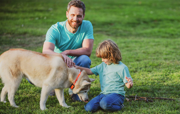 Father and son with pet dog relaxing on nature in park. - Foto, afbeelding
