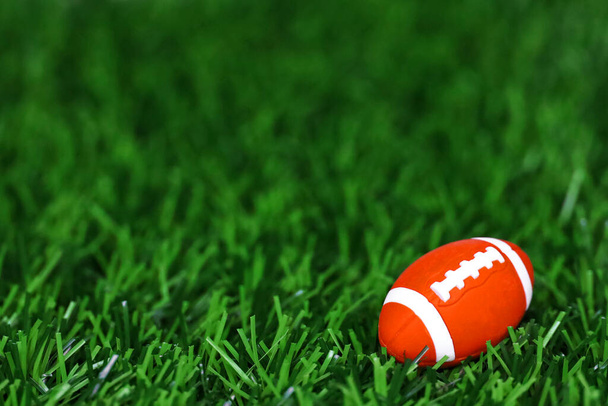 Martwa natura zdjęcie miniaturowej zabawki Amerykańska piłka nożna umieszczona na sztucznej trawie - Zdjęcie, obraz