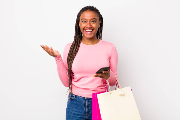 young adult black woman feeling happy, surprised realizing a solution or idea. shopping bags concept - Foto, Imagem