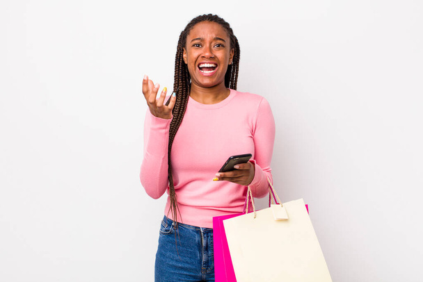 young adult black woman looking desperate, frustrated and stressed. shopping bags concept - Foto, Imagem