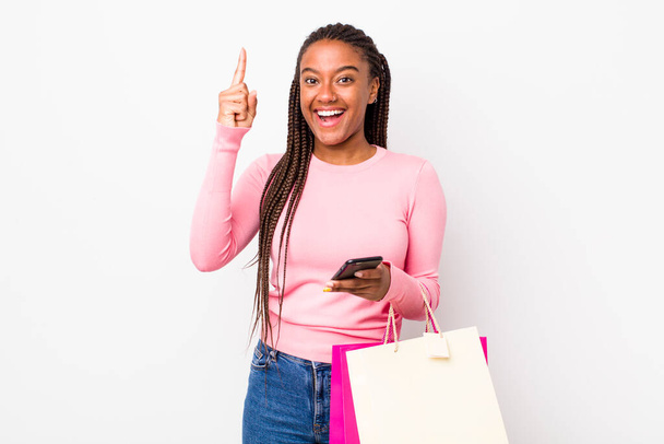 young adult black woman feeling like a happy and excited genius after realizing an idea. shopping bags concept - Fotó, kép