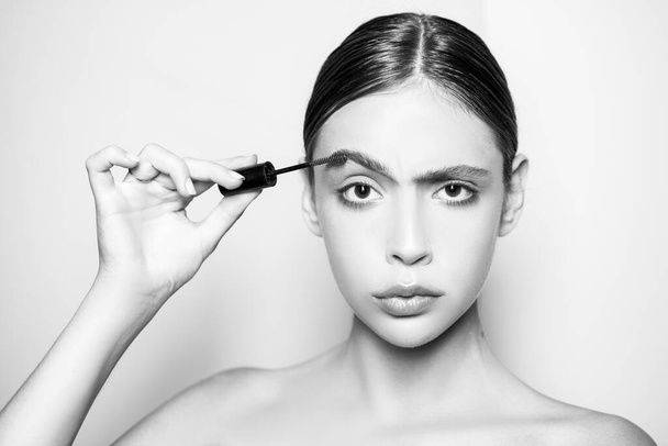 Young beautiful woman does natural brow makeup. Portrait of girl with professional nude makeup and perfect smooth healthy skin. Beautiful girl using brow gel for her brow makeup. - 写真・画像