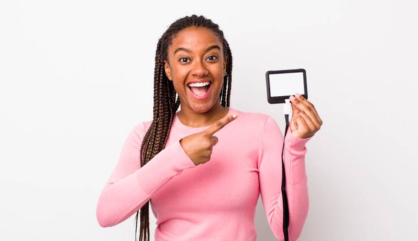 young adult black woman looking excited and surprised pointing to the side. vip pass id concept - Fotografie, Obrázek