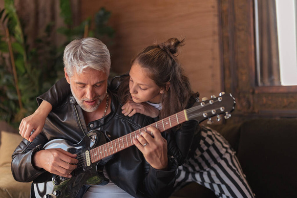 Father learning his teenage daughter to play the electric guitar at home. - Foto, Bild