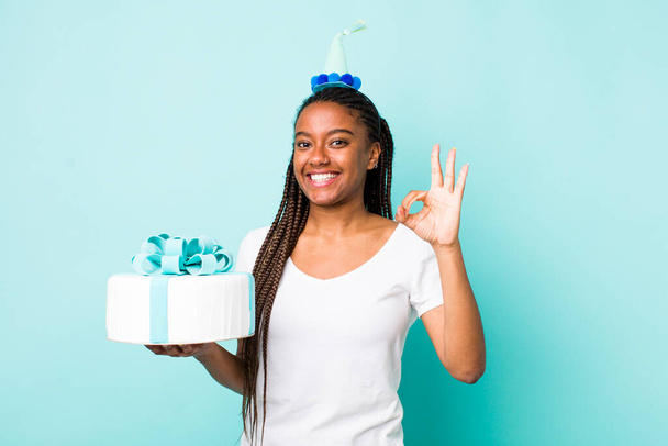 young adult black woman feeling happy, showing approval with okay gesture. birthday concept - Foto, afbeelding