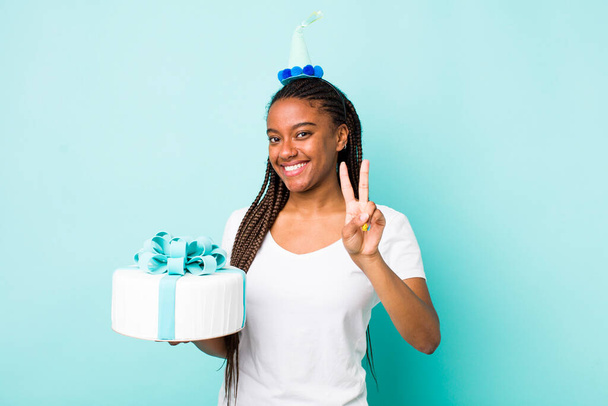 young adult black woman smiling and looking friendly, showing number two. birthday concept - 写真・画像
