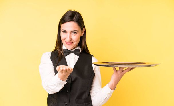 young adult pretty woman smiling happily with friendly and  offering and showing a concept. waiter and tray concept - Foto, afbeelding