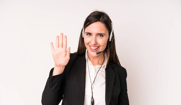 young adult pretty woman smiling happily, waving hand, welcoming and greeting you. telemarketer concept - Photo, image