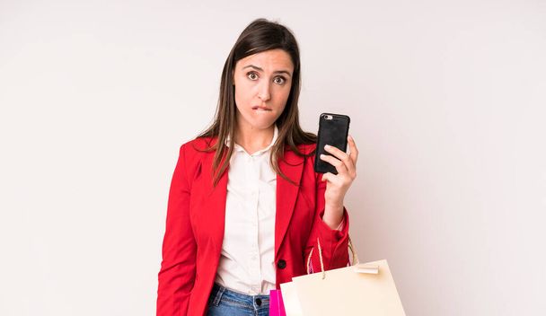 young adult pretty woman looking puzzled and confused. shopping bags concept - Foto, afbeelding