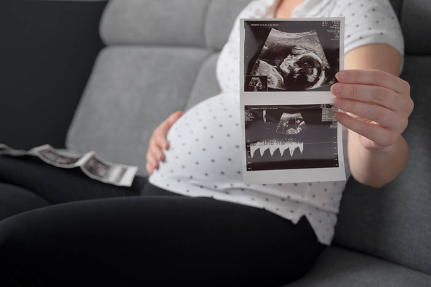 Schwangere auf Sofe mit Ultraschallbild - Foto, Bild
