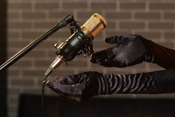 Mains féminines et microphone professionnel sur fond sombre, gros plan - Photo, image