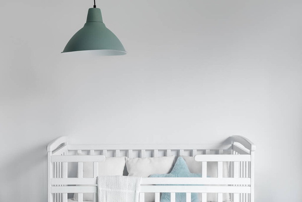 Удобная кроватка возле белой стены в детской комнате - Фото, изображение