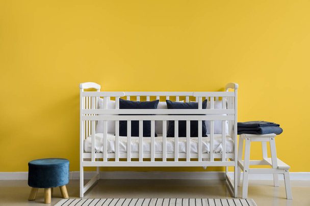 Stylish interior of children's room with comfortable crib near yellow wall - Photo, Image