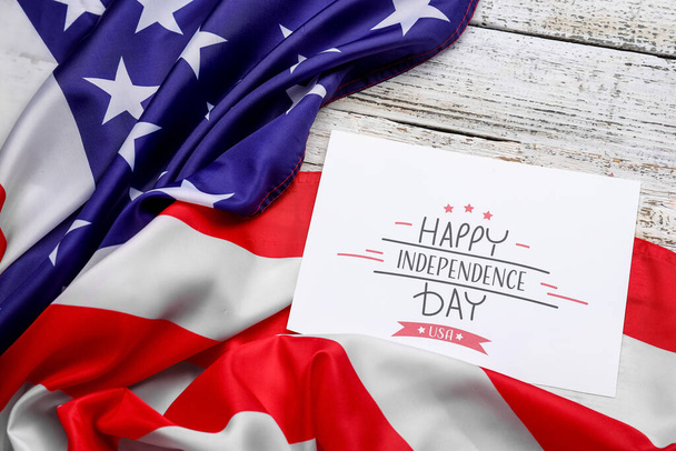 Wenskaart met tekst HAPPY INDEPENDENCE DAY en USA vlag op witte houten ondergrond - Foto, afbeelding