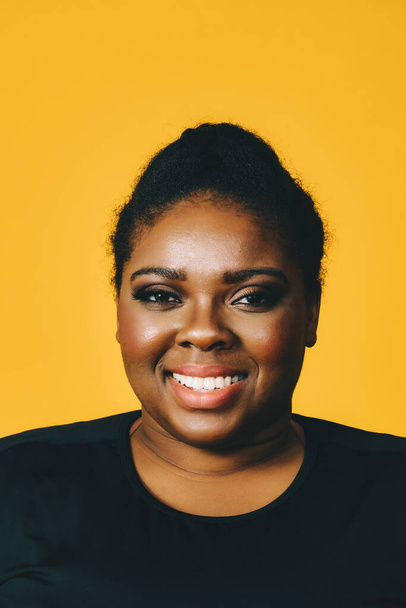 retrato de uma bela jovem afro-americana sorrindo isolado sobre fundo amarelo - Foto, Imagem