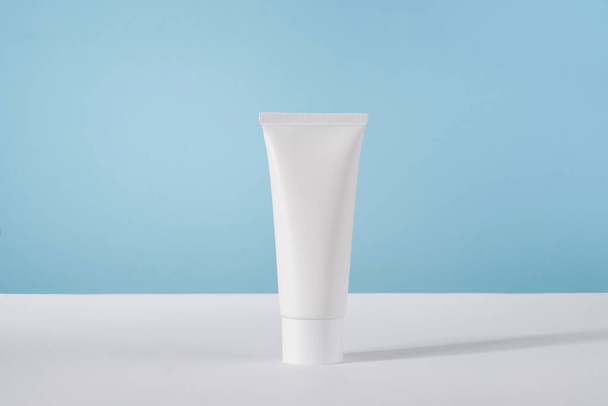 Moisturiser hand cosmetic cream white plastic tube mockup on blue background front view. Blank body and health care beauty product packaging - Photo, Image