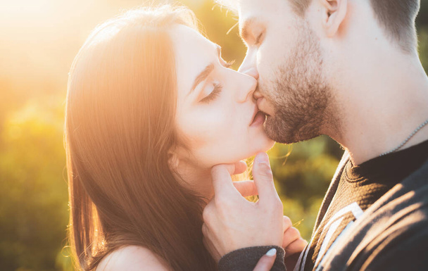 若いロマンチックなカップルのクローズアップはキスです。秋の夕日に目を閉じてキスしながら愛を表現し、愛情の美しい人々のプロフィール. - 写真・画像