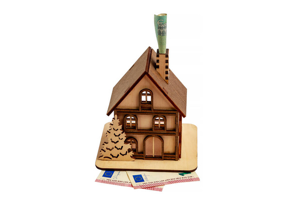 Euro számla egy kéményben és egy fa játék szimbolikus ház fehér elszigetelt háttérrel. Fűtés - Fotó, kép