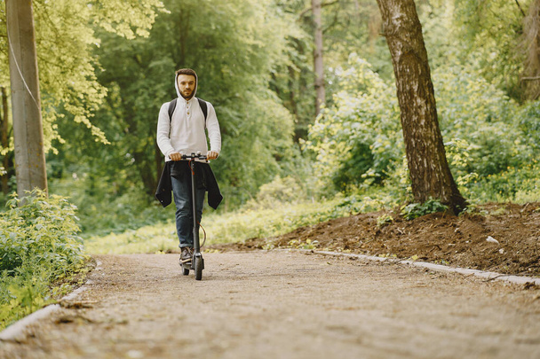 The guy rides an electric scooter in the summer Pforest - 写真・画像