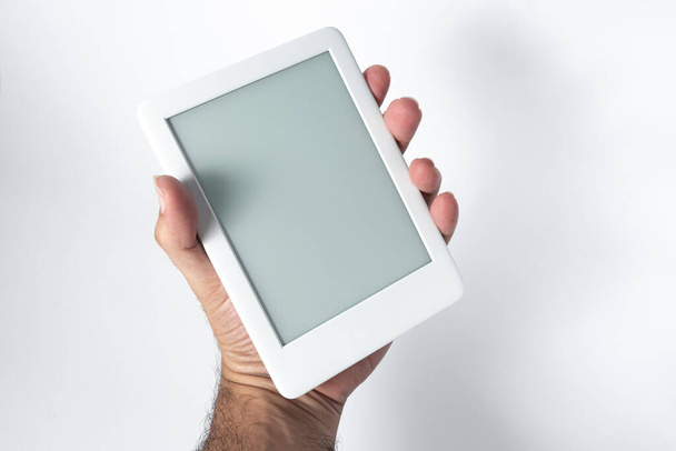 Ebook reader over geïsoleerde witte achtergrond - wordt vastgehouden door een mannelijke hand - Foto, afbeelding